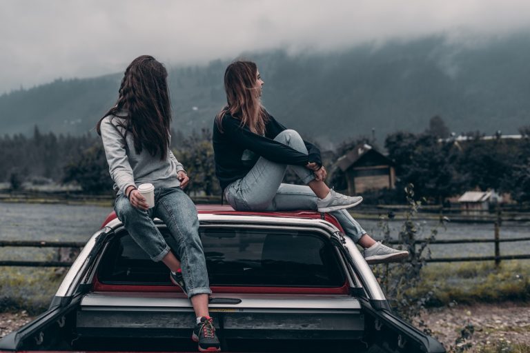 two woman sitting at a car roof